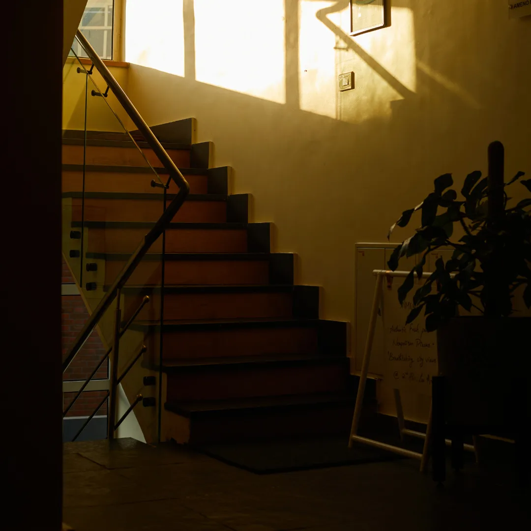 Golden evening light falling across the café staircase through a paned window