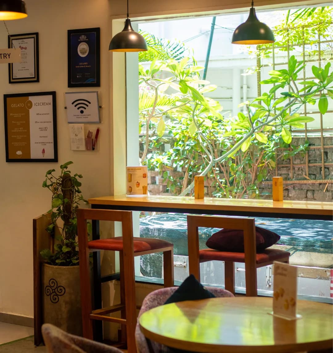 Window bar seating with cushioned stools, framed awards on the wall and greenery outside
