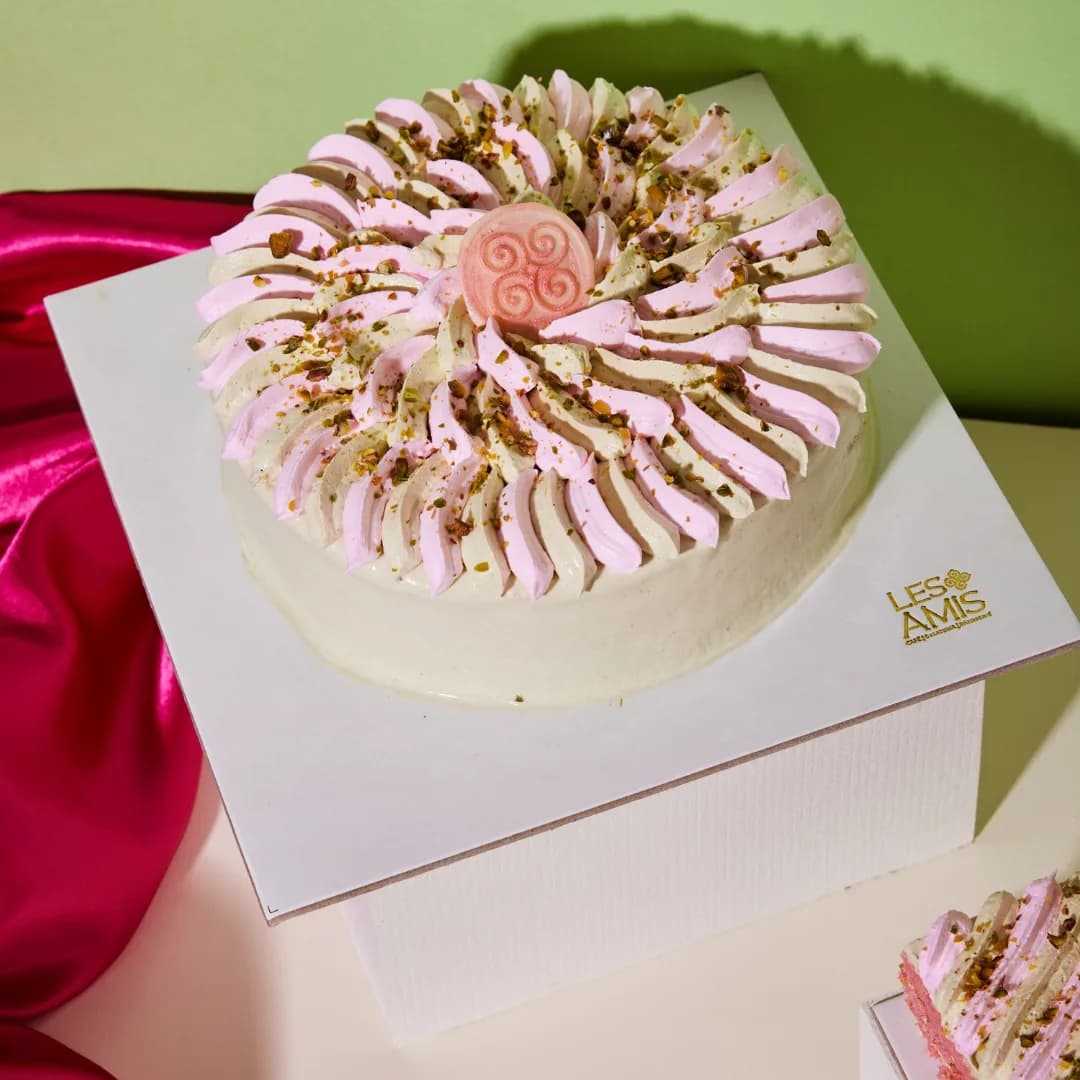 The rose–pistachio cake — piped petals of pink and pistachio cream dusted with crushed nuts
