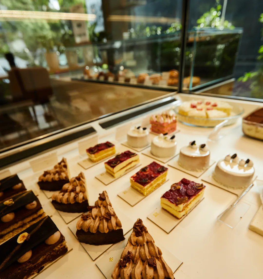The patisserie display case — entremets, tea cakes and tarts lined up under glass